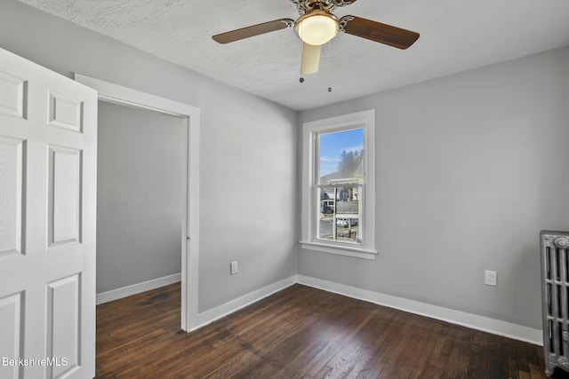 unfurnished bedroom featuring a textured ceiling, dark wood-type flooring, baseboards, and a ceiling fan