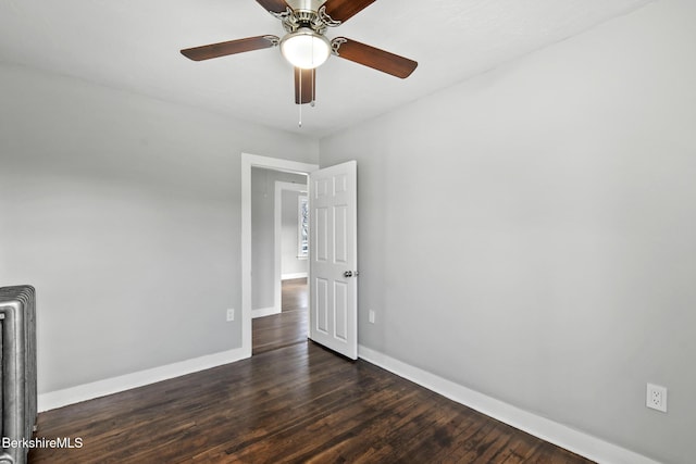 spare room featuring ceiling fan, baseboards, radiator, and wood finished floors