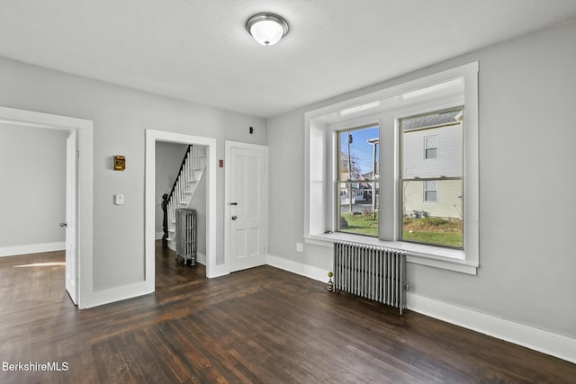 unfurnished bedroom with radiator heating unit, baseboards, and wood finished floors