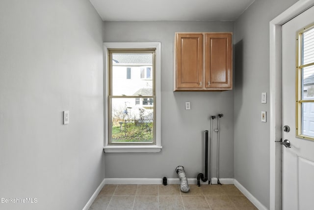 laundry area featuring light tile patterned flooring, cabinet space, and baseboards