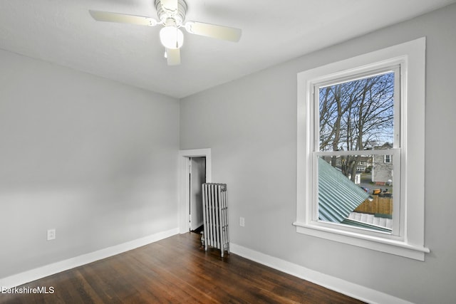 spare room with dark wood finished floors, a ceiling fan, radiator heating unit, and baseboards