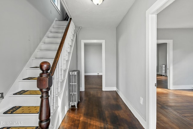 hall with stairway, radiator heating unit, baseboards, and wood finished floors