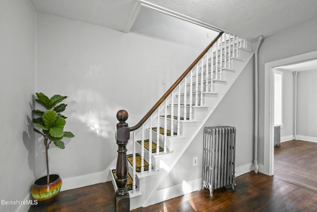 stairs featuring radiator heating unit, baseboards, and wood finished floors