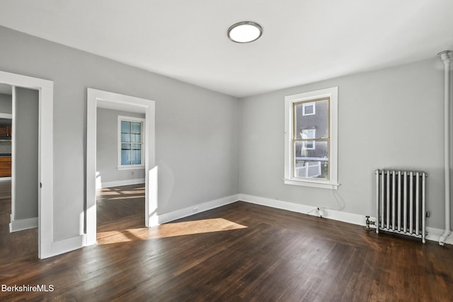 spare room with baseboards, wood finished floors, and radiator heating unit