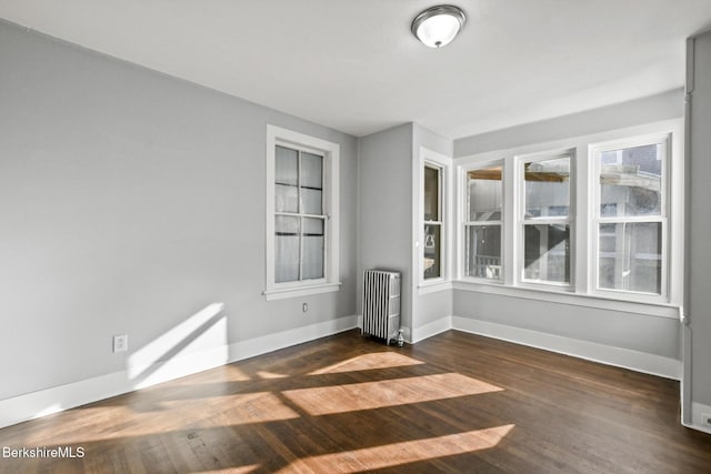 unfurnished room with radiator heating unit, baseboards, and wood finished floors