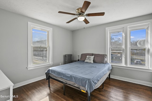 bedroom with radiator, a ceiling fan, baseboards, and wood finished floors