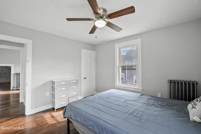 bedroom with ceiling fan, baseboards, radiator, and wood finished floors