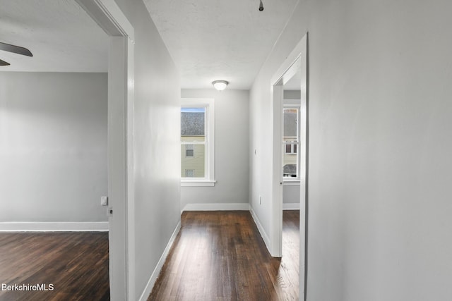 hall with baseboards and wood-type flooring