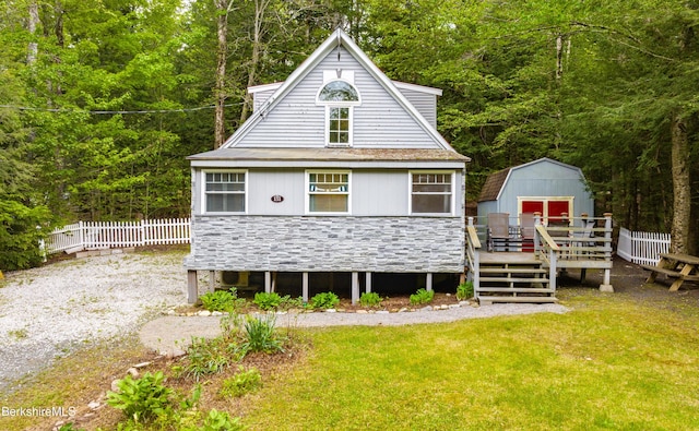 151 Excalibur Dr, Becket, MA 01223 - rear view of house with stone siding, a wooden deck, and a view of trees