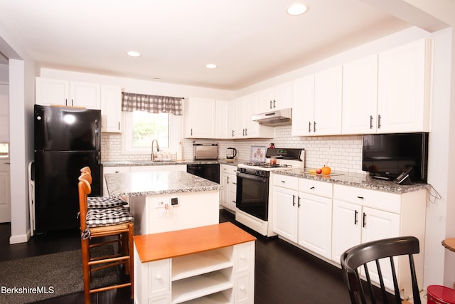 kitchen featuring black appliances, light stone countertops, white cabinetry, and sink