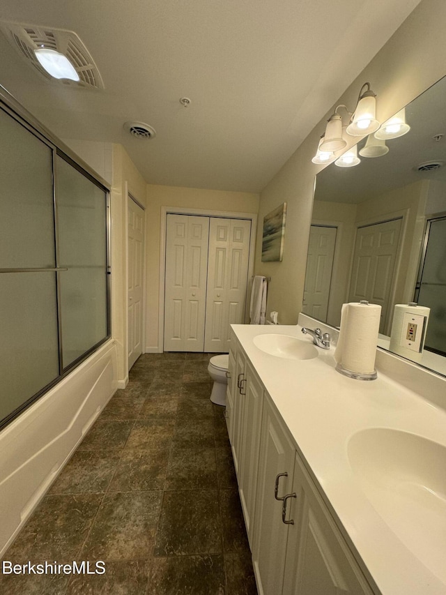 full bathroom with shower / bath combination with glass door, vanity, an inviting chandelier, and toilet