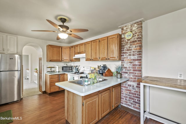 kitchen featuring under cabinet range hood, stainless steel appliances, ceiling fan, a peninsula, and dark wood finished floors