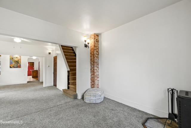 unfurnished living room with arched walkways, stairway, carpet floors, and baseboards