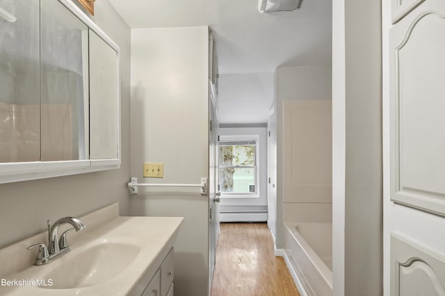 bathroom with wood finished floors, a baseboard radiator, a tub, vanity, and a shower