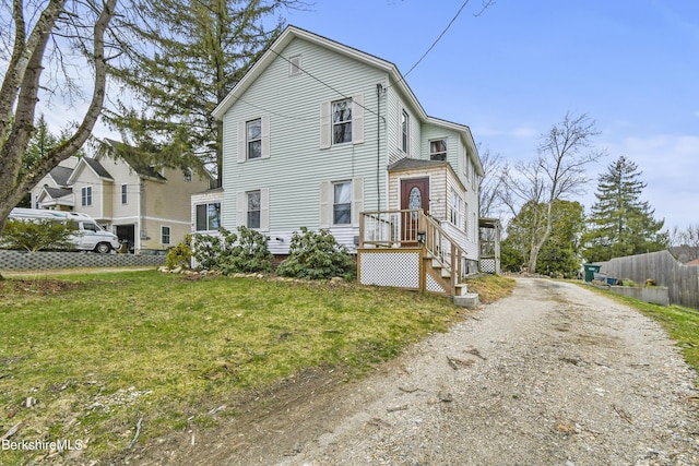 view of front of property with a front yard, dirt driveway, and fence