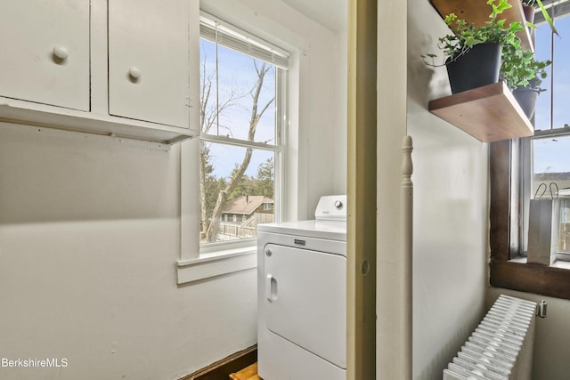 clothes washing area with radiator heating unit, washer / dryer, and laundry area