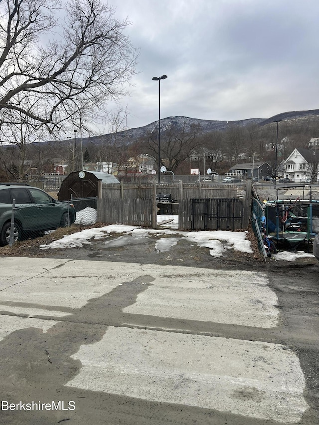 view of street featuring a mountain view, street lights, and a gate