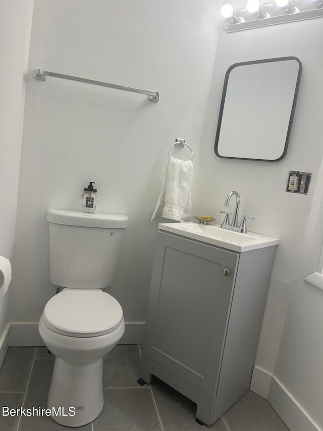 half bathroom featuring baseboards, toilet, vanity, and tile patterned flooring