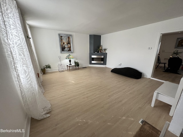 living room with a fireplace, baseboards, and wood finished floors