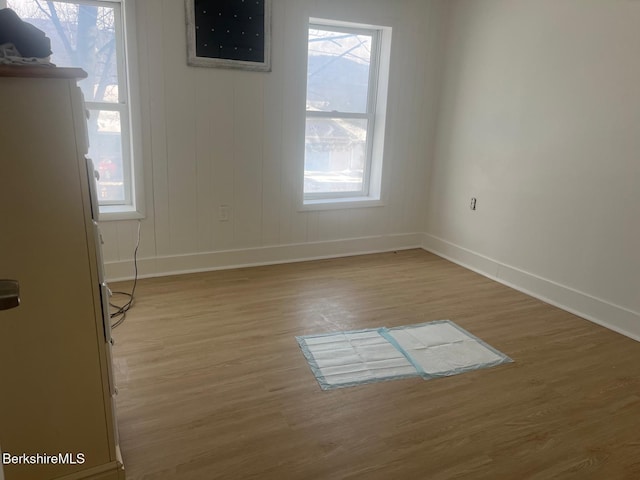 empty room featuring baseboards, light wood-style floors, and a healthy amount of sunlight