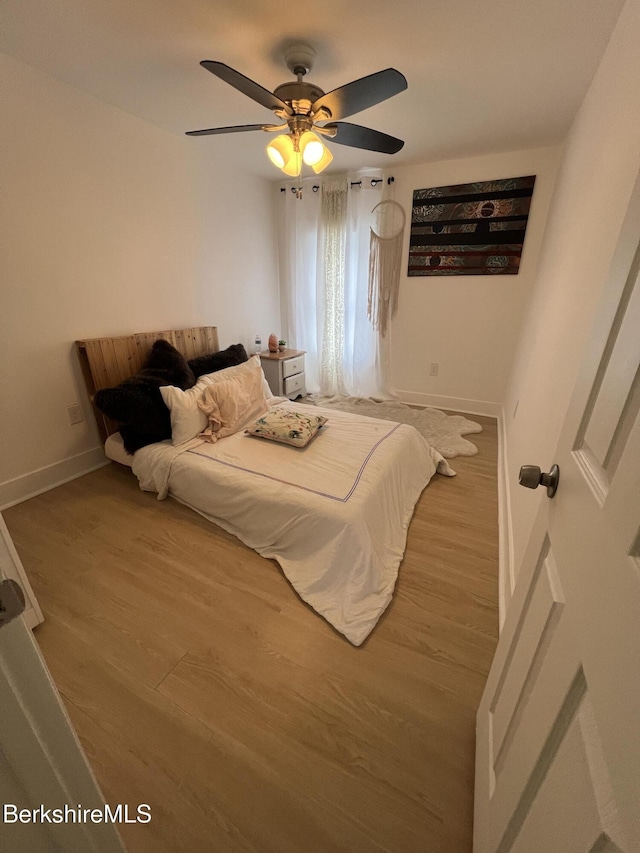 bedroom featuring wood finished floors, baseboards, and ceiling fan