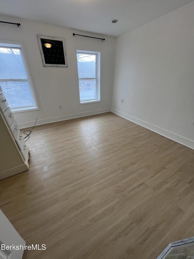 spare room featuring light wood-type flooring and baseboards