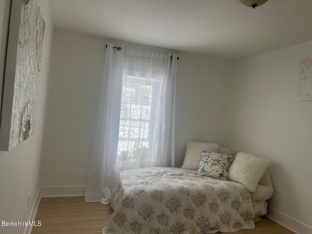 bedroom featuring multiple windows, light wood-type flooring, and baseboards