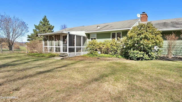 back of property featuring a yard, fence, a sunroom, and a chimney