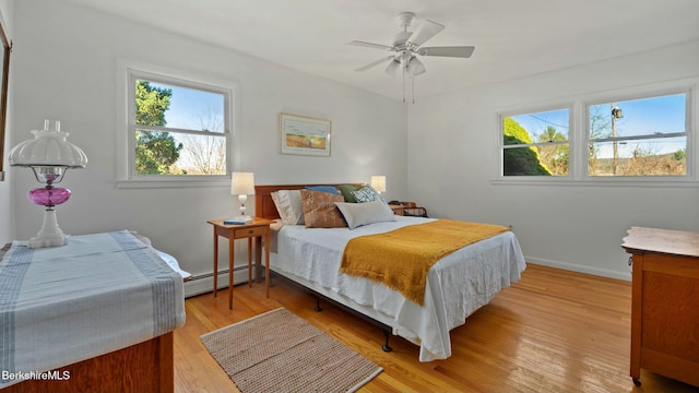 bedroom featuring light wood-style floors, baseboards, baseboard heating, and a ceiling fan