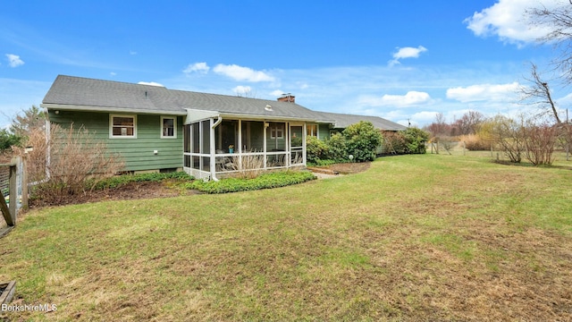back of house featuring a yard, a sunroom, and a chimney