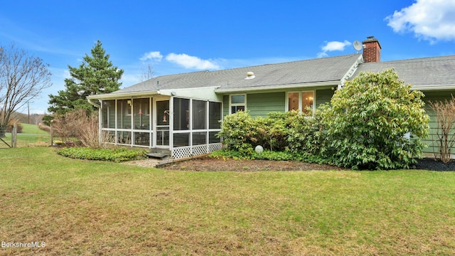 rear view of house featuring a yard, fence, a sunroom, and a chimney