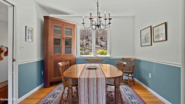 dining area with light wood finished floors, a notable chandelier, and baseboards