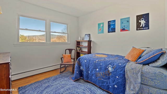 bedroom featuring baseboard heating and wood finished floors