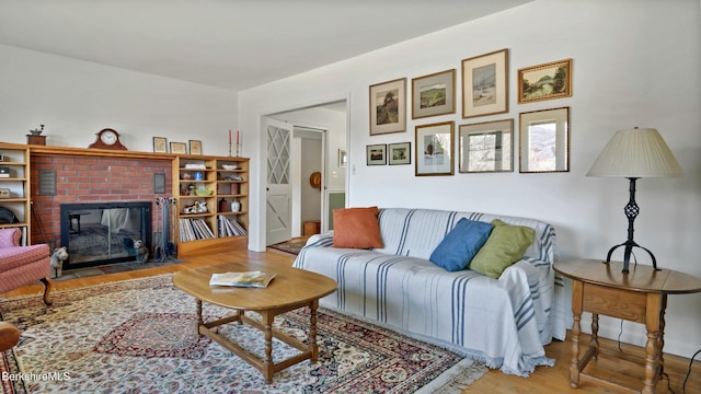 living area with a brick fireplace and wood finished floors