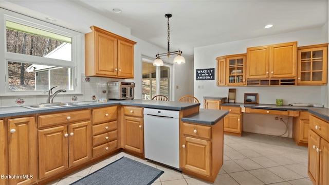 kitchen featuring dishwasher, a sink, dark countertops, a peninsula, and pendant lighting