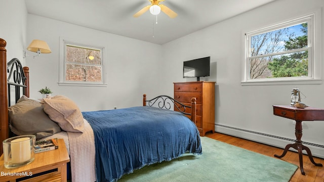 bedroom with a baseboard radiator and wood finished floors