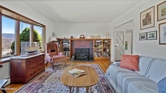 living room with a fireplace, light wood-style floors, and baseboard heating