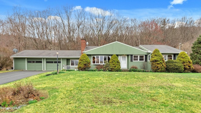 view of front facade featuring a garage, driveway, a chimney, and a front lawn