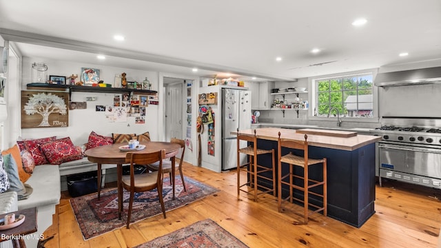32 S Main Rd, Otis, MA 01253 - kitchen featuring freestanding refrigerator, open shelves, high end stove, wall chimney exhaust hood, and light wood-style flooring