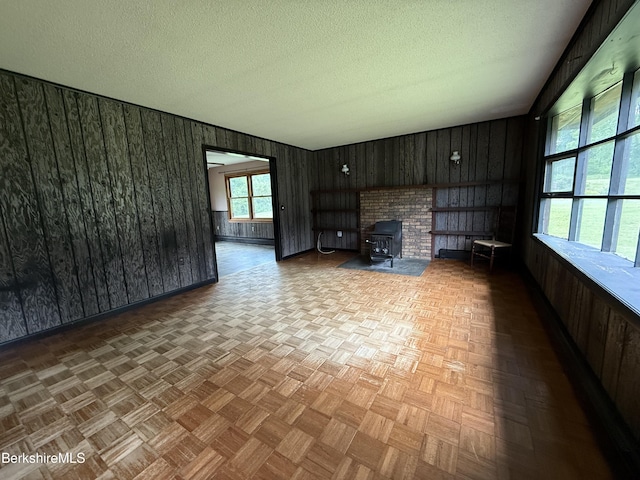 153 Dugway Rd, Lenox, MA 01240 - unfurnished living room with wooden walls, a textured ceiling, and a wood stove