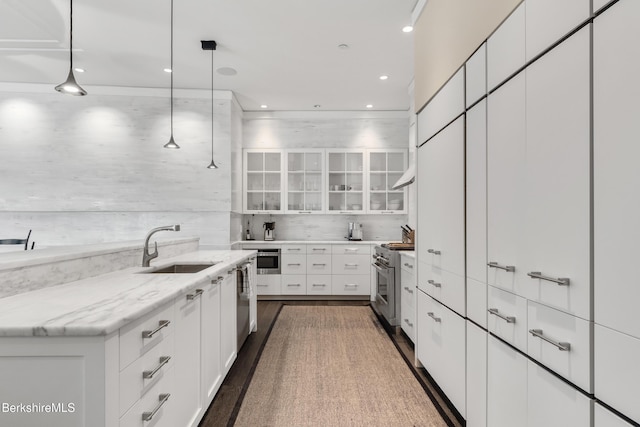 kitchen with appliances with stainless steel finishes, decorative light fixtures, white cabinetry, sink, and light stone counters