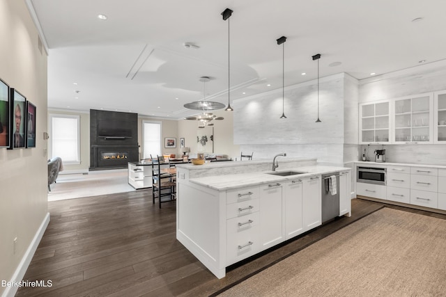 kitchen featuring pendant lighting, sink, dishwasher, light stone countertops, and white cabinets