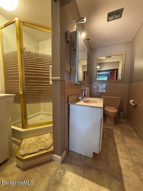 53 Churchill Crst Unit 53, Pittsfield, MA 01201 - bathroom featuring a shower stall, vanity, tile walls, and wainscoting