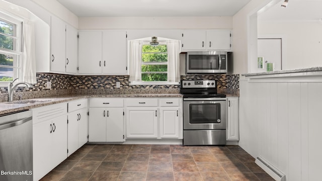 85 Wilson St, Pittsfield, MA 01201 - kitchen featuring appliances with stainless steel finishes, baseboard heating, white cabinetry, backsplash, and light stone countertops