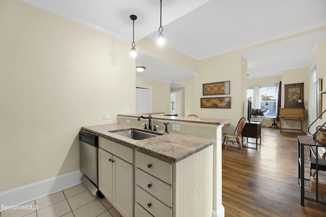 kitchen featuring white cabinets, sink, hanging light fixtures, stainless steel dishwasher, and kitchen peninsula