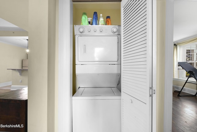 washroom with hardwood / wood-style floors, crown molding, and stacked washer and dryer