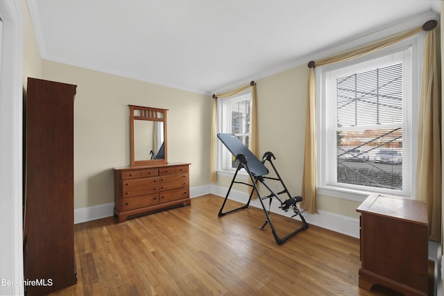 workout area with light wood-type flooring and ornamental molding