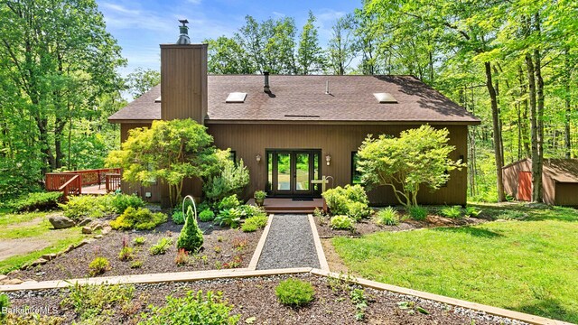 889 George Carter Rd, Becket, MA 01223 - view of front of home with french doors, a shingled roof, a deck, a chimney, and a front lawn