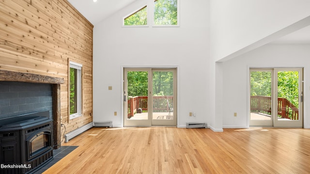 889 George Carter Rd, Becket, MA 01223 - unfurnished living room featuring high vaulted ceiling, a wood stove, a baseboard heating unit, wood finished floors, and wooden walls