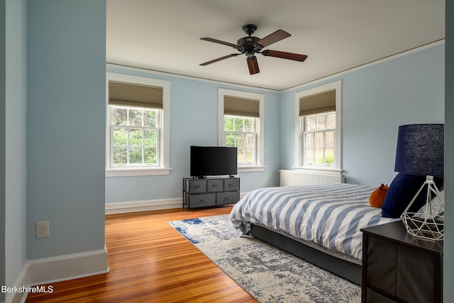 bedroom featuring ornamental molding, wood finished floors, baseboards, and ceiling fan